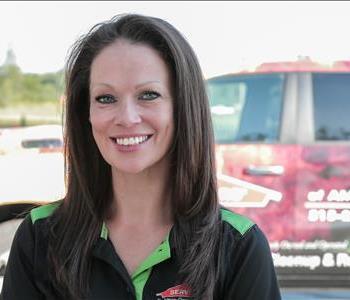 Female employee Lori Newhouse in front of SERVPRO truck in background
