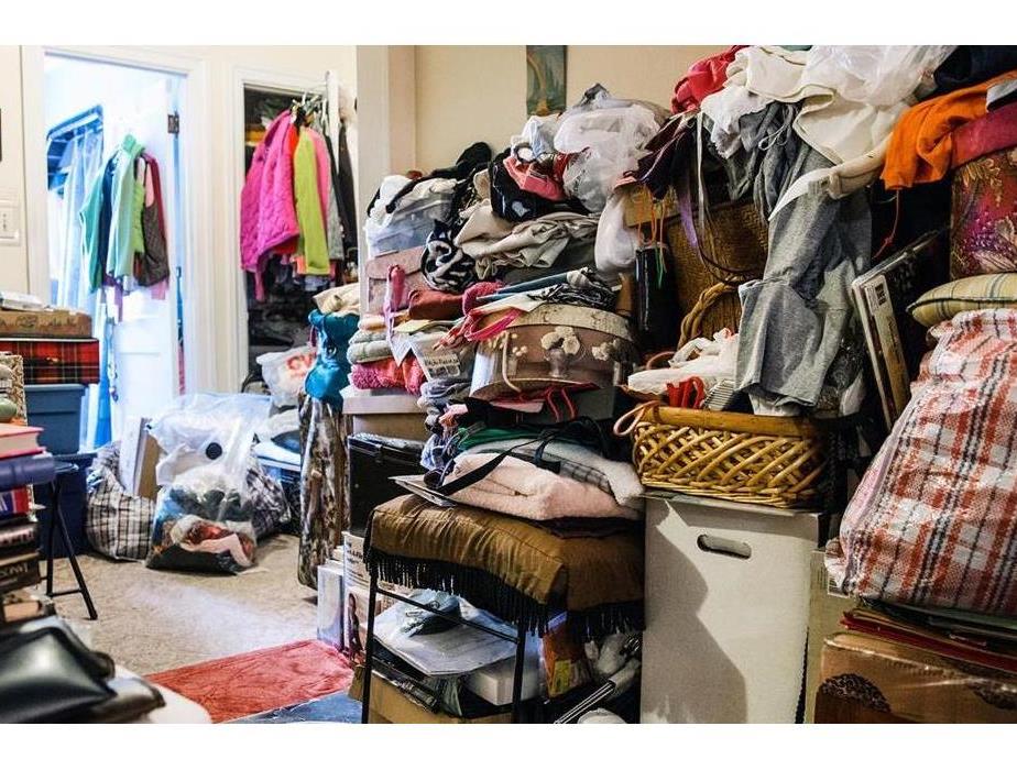 A bedroom cluttered with clothes and other miscellaneous items 