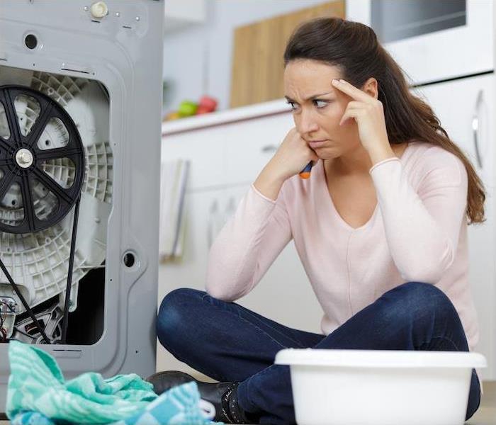 frustrated woman on floor looking at broken washer